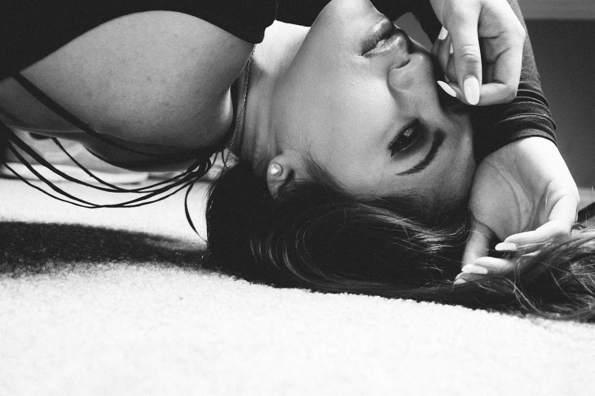 Black and white photo of a woman lying on a textured surface.